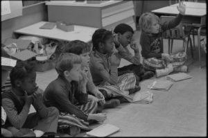 First grade class of African American and white school children seated on the floor