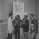 Men playing guitars and singing at the Abraham Lincoln statue inside the Lincoln Memorial during the March on Washington